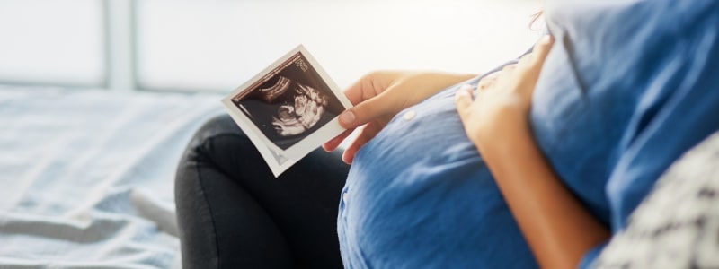 Pregnant woman looks at ultrasound photo