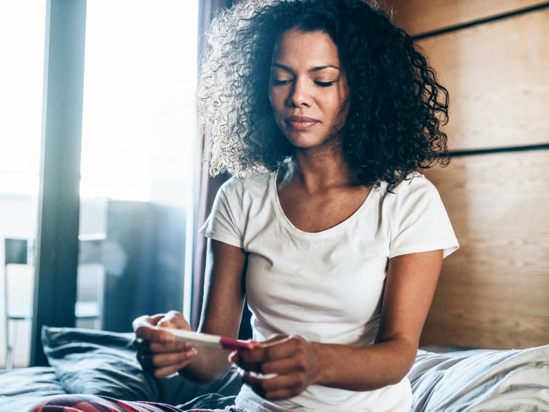 Woman looks pensively at the results of a pregnancy test
